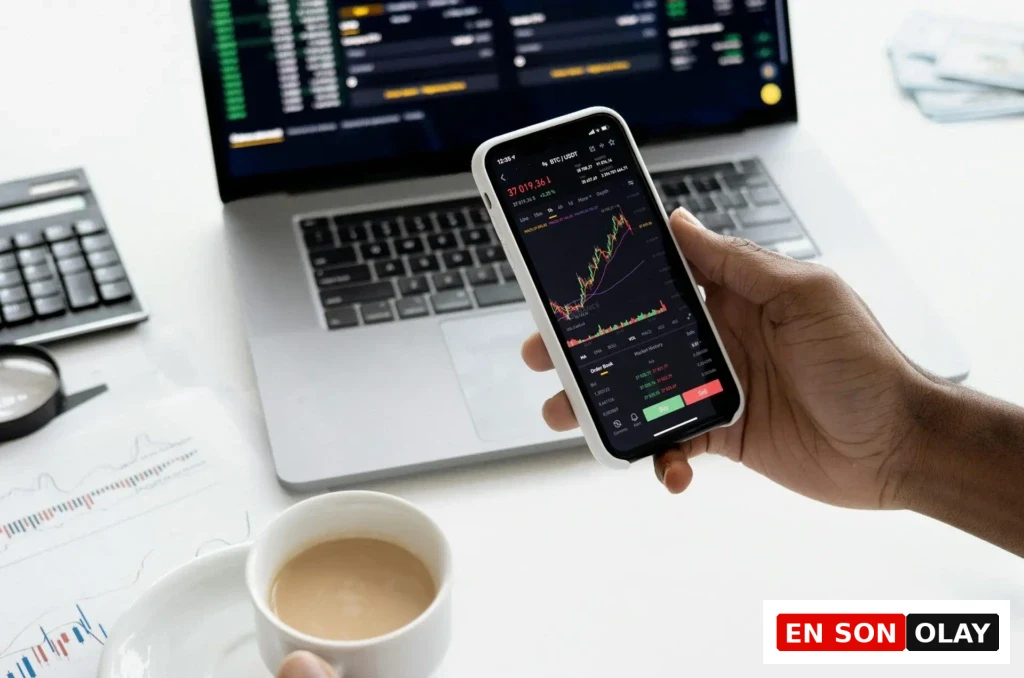 Bir kişi, mobil uygulama üzerinden kripto para grafiklerini incelerken aynı anda dizüstü bilgisayar ekranında piyasa verilerini takip ediyor.