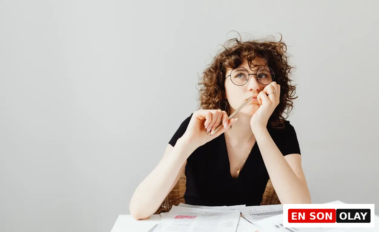 Ensonolay Akşam Yemeğinde Ne Yiyeceğine Karar Veremeyenler İçin: Yatırımda Karar Yorgunluğunu Bitirmek: Masasına yayılmış finansal grafikler arasında elinde kalemiyle dalgınca düşüncelere dalan gözlüklü genç kadın, sayısız yatırım seçeneğinin yarattığı zihinsel karar yorgunluğunu yansıtıyor.
