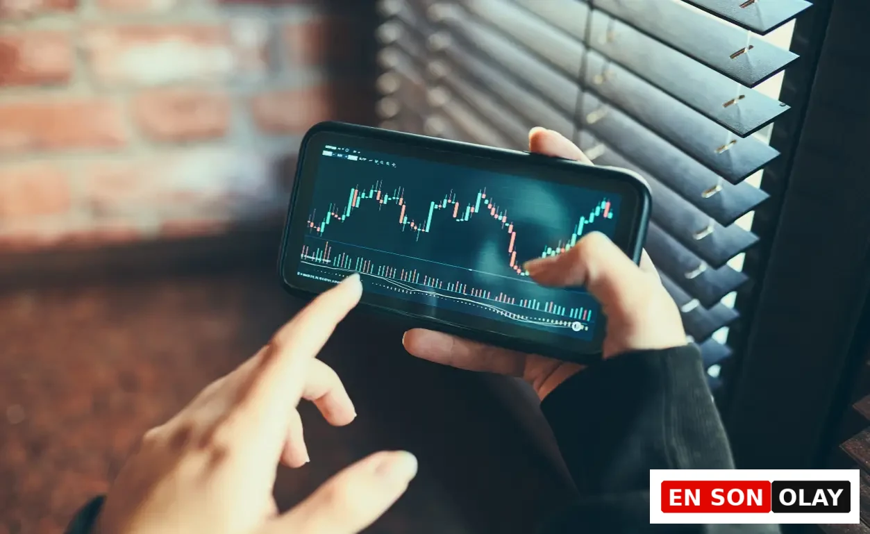 Finansal piyasalardaki karmaşık veri grafiklerini gösteren bir akıllı telefonu parmaklarıyla aktif olarak inceleyen bir kişi, sürekli veri akışıyla ortaya çıkan karar yorgunluğunun potansiyel etkilerini yansıtıyor.