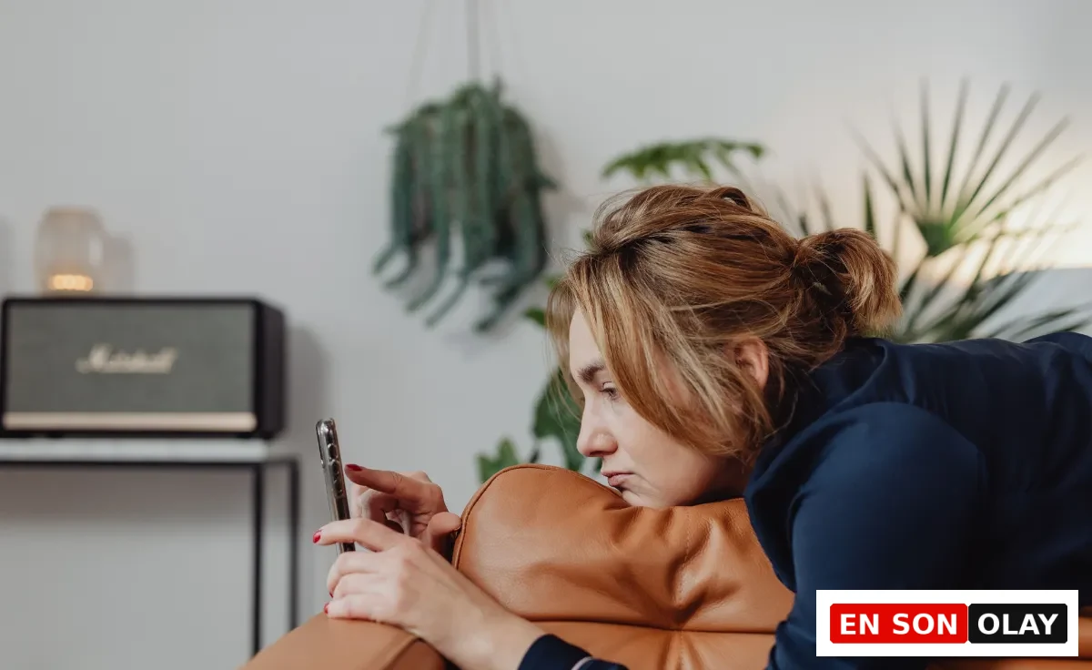 Kahverengi deri kanepede uzanmış, eliyle telefon ekranını kaydıran, yüzünde yorgun veya sıkılmış bir ifade olan bir kadın, modern çağın getirdiği dijital bağımlılık ve sürekli yapay uyarılmanın yol açtığı dopamin dengesizliği veya dopamin direnci sorununa işaret ediyor.
