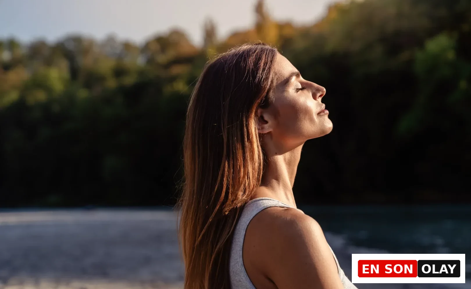 Güneşin altında gözleri kapalı, yüzü yukarı dönük, enerjik ve sağlıklı görünen uzun saçlı bir kadın, B12 vitamini eksikliği belirtileri ile mücadele ederek takviyesi sayesinde optimal seviyelere ulaşmış ve zihinsel berraklık kazanmış bir hali yansıtıyor.