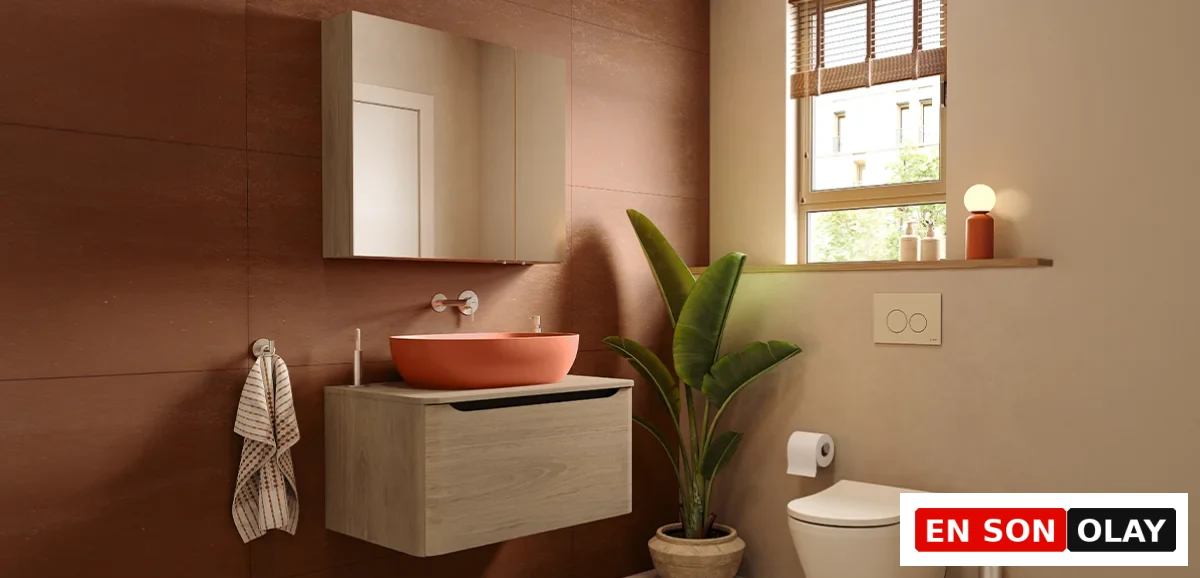 Modern bir banyoda, açık renkli ahşap görünümlü çift lavabo dolabı ve beyaz lavabolar ile uyumlu, koyu renkli metal armatürler ve çerçeveli yuvarlak aynaların şık kontrastı, duvar ve zemin gibi farklı dokulu yüzeylerle birleşerek banyoda renk uyumu sağlayan Mix & Match yaklaşımını görselleştiriyor.