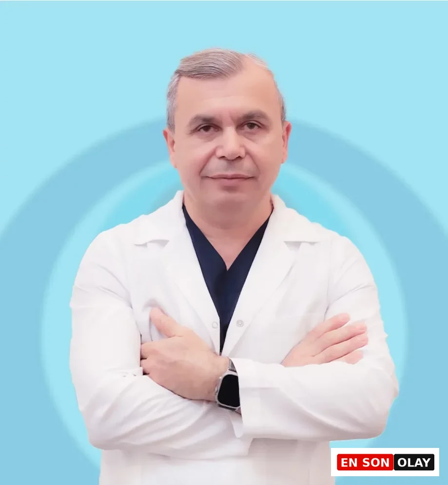 Halil Genç, lacivert cerrahi forma üzerine beyaz önlük giymiş, kollarını göğsünde kavuşturmuş ve ciddi bir ifadeyle doğrudan kameraya bakarken, arkasında açık mavi tonlarda dairesel desenli bir arka plan yer alıyor.