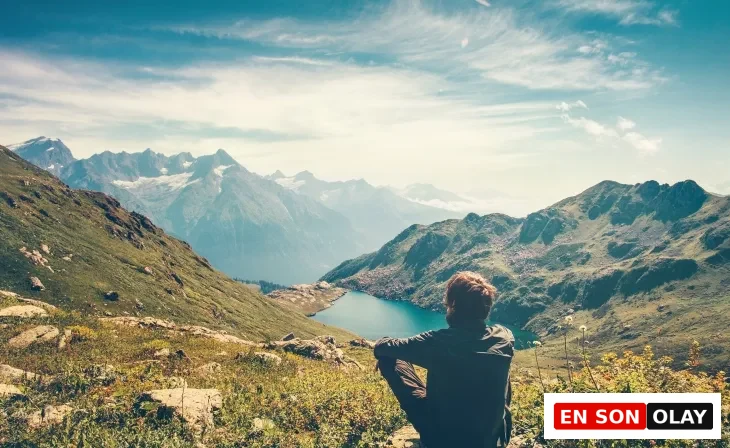 Uzaklarda uzanan bir vadi manzarasına bakan yürüyüşçü. Sessizlik, meditasyon ve iç yolculuk hissi.