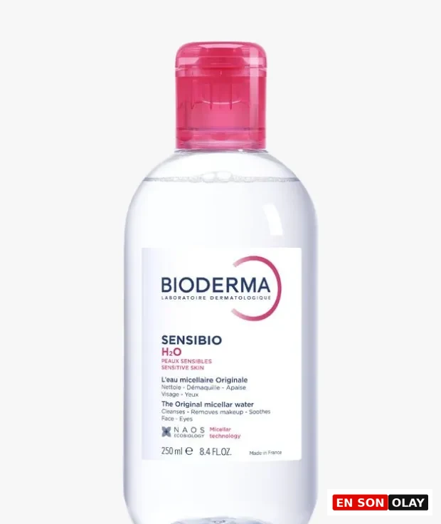 Beyaz etiketinde Bioderma Sensibio H2O ibaresi ve hassas ciltler için olduğu belirtilen, parlak pembe kapaklı, şeffaf, 250 ml'lik bir misel su şişesi temiz beyaz bir zemin üzerinde dikey olarak gözüküyor.