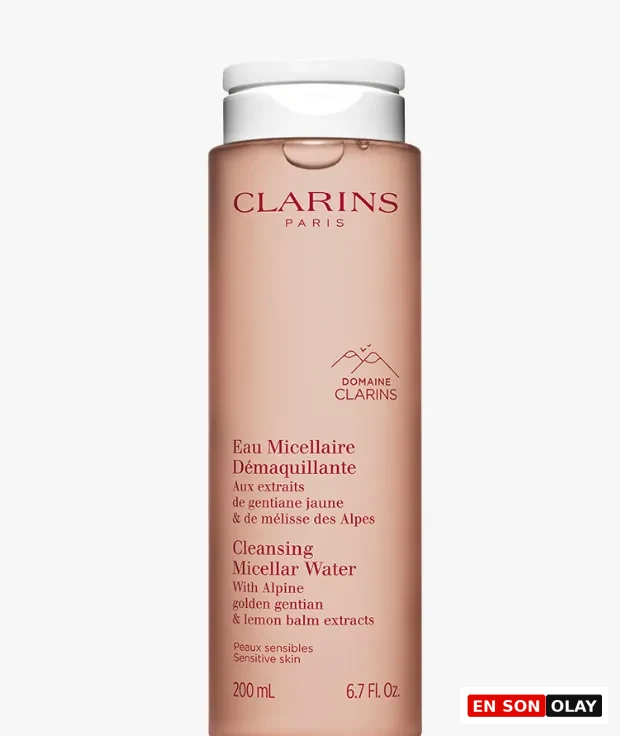 Aydınlık gri bir zeminde dik duran, yarı saydam şeftali pembesi renginde, beyaz kapaklı Clarins micellar su şişesi, üzerinde marka adı, 'Cleansing Micellar Water' ibaresi, 'Alpine golden gentian & lemon balm extracts' bilgisi ve hassas ciltler için olduğu notuyla birlikte 200 ml hacmini gösteriyor.