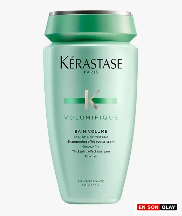 Açık mint yeşili renkte, üst kısmı koyu yeşil ve gümüş detaylı kapaklı Kerastase markasının Volumifique serisinden, özellikle ince telli saçlara hacim ve dolgunluk katmak üzere tasarlanmış 250 ml'lik bir hacim şampuanı şişesi beyaz bir arka plan üzerinde dikkat çekici şekilde duruyor.