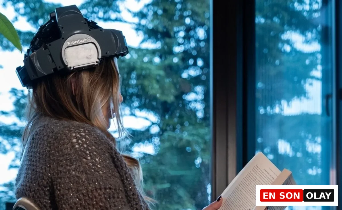 Pencere kenarında oturmuş, başına takılı WeberBrain nörofeedback cihazı ve elinde bir kitapla, uzun ömür ve zihinsel sağlık rehberi kapsamında beyin aktivitesini destekleyerek okuma yapan sarışın bir kadın.