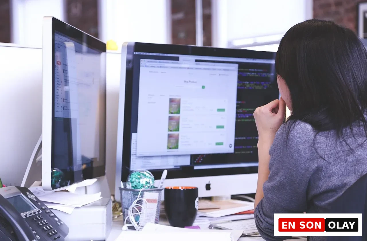 Çift ekranlı ofis ortamında çalışan kişi, yapay zekâ destekli iş süreçlerini yönetiyor.