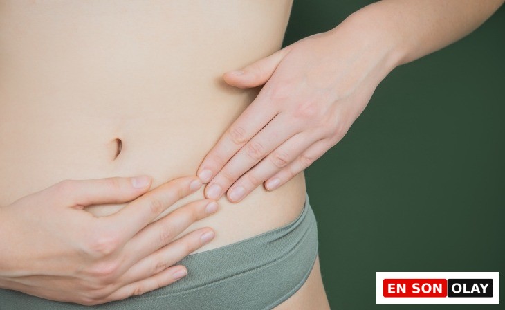 Alt karın bölgesine dokunan kadın eli; yumurtalık ağrısı, çikolata kisti veya endometriozis gibi jinekolojik rahatsızlıklara dikkat çeken temsili görsel.