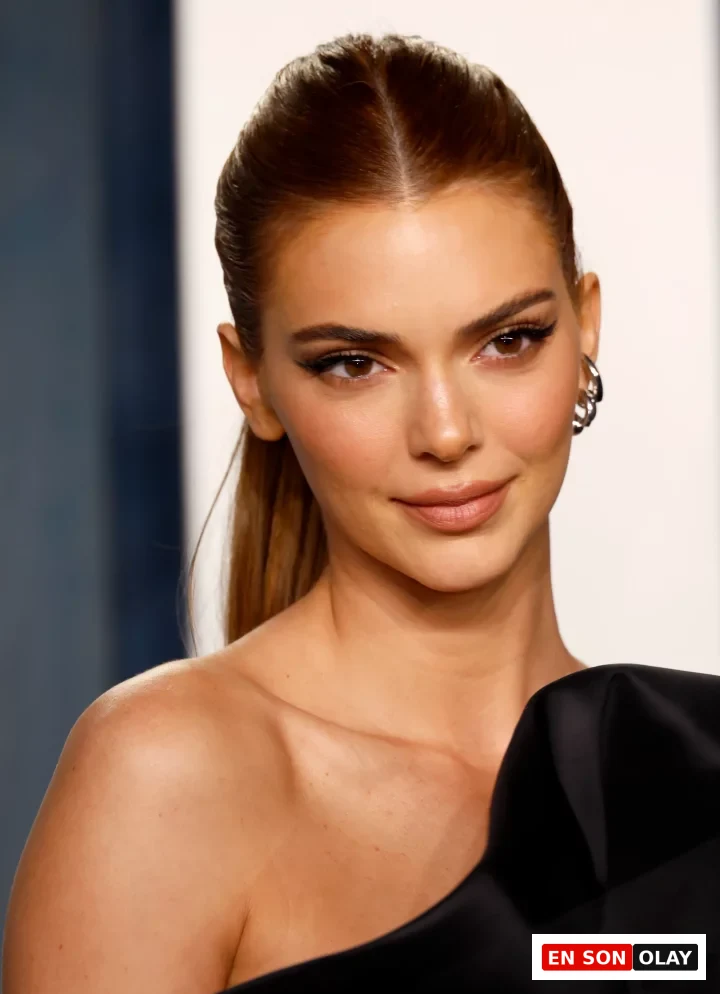 Kendall Jenner, ortadan ayrılmış, sıkıca arkaya toplanmış parlak karamel tonlarındaki saçları, sade ama şık makyajı ve omuzları açık siyah elbisesiyle esmer tenlilere yakışan modern saç renklerinden birini sergiliyor.