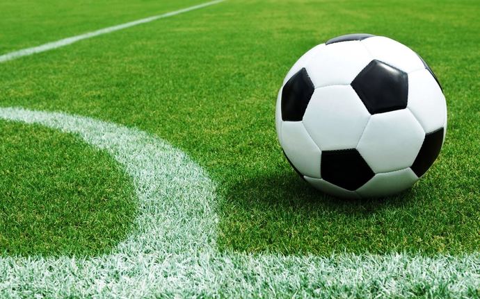 Soccer ball resting on a green grass field next to a white sideline.