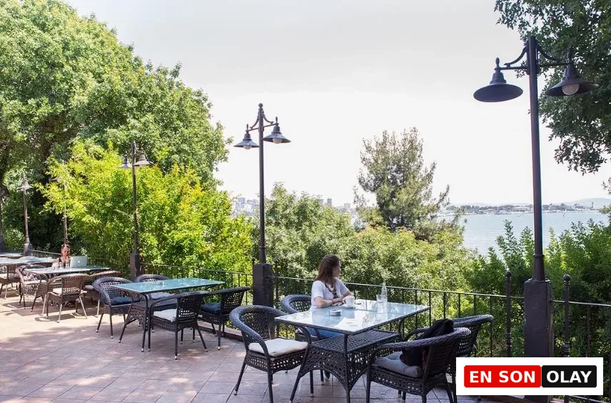 Moda'daki Bomonti Çay Bahçesi'nin ağaçlarla çevrili terasından görünen sakin Boğaz manzarasına karşı, cam masa ve koyu renk hasır sandalyelerin birinde oturan bir kadın, elindeki kahvesiyle günün erken saatlerinde İstanbul'un huzurlu çalışma mekânlarından birinde keyifli bir an geçiriyor.