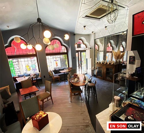 Han Karaköy'ün modern avizelerle aydınlatılmış ferah iç mekânında, renkli kemerli pencerelerle sokağa bakan, hem bireysel hem de grup çalışmasına uygun masaların bulunduğu, sakin ve ilham verici bir çalışma mekânı görülüyor.