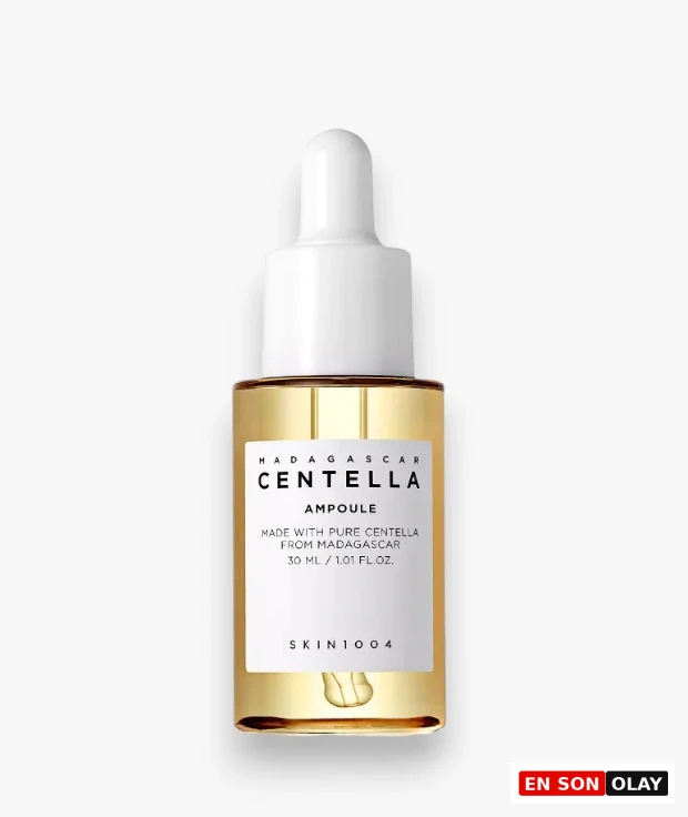 Beyaz kapaklı ve damlalıklı şeffaf bir cam şişede sunulan, altın sarısı renkteki SKIN1004 Madagaskar Centella Ampul serumu, üzerinde 30 ml hacmi ve saf Centella içeriği yazan beyaz etiketiyle cilt bakımı rutinleri için hazır bir şekilde duruyor.