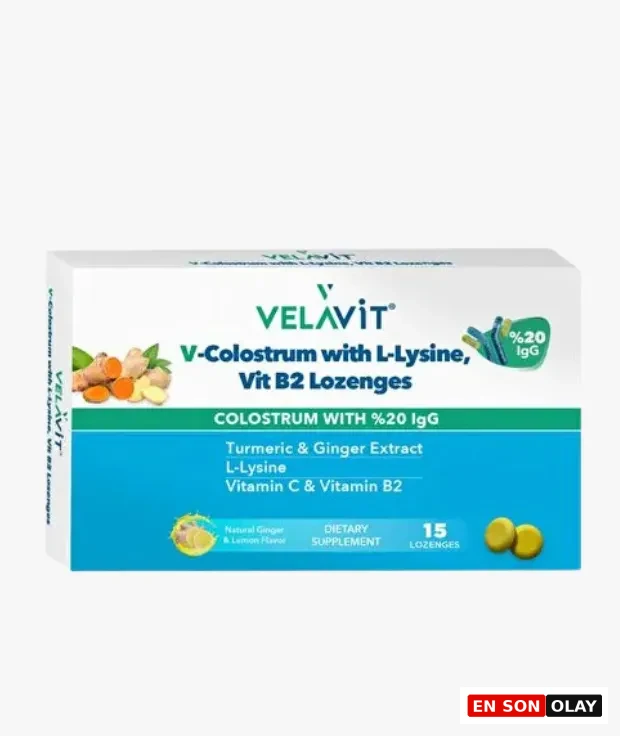 Beyaz bir kutu ambalajında sunulan, içeriğinde zerdeçal ve zencefil ekstraktı bulunan Velavit V-Colostrum L-Lizin Vit B2 pastil takviyesi, 15 adet pastil içererek genel wellness ve bağışıklık sistemine destek için tasarlanmıştır.