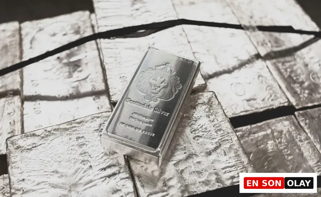 Parlak yüzeyli, üzerinde aslan figürü ve Scottsdale Silver yazısı bulunan bir gümüş külçesi, çevresindeki daha ham ve işlenmemiş birçok gümüş külçesinin üzerine konumlanmış olarak gümüş yatırımının hem tarihi önemini hem de günümüzdeki yaygınlığını gözler önüne seriyor.