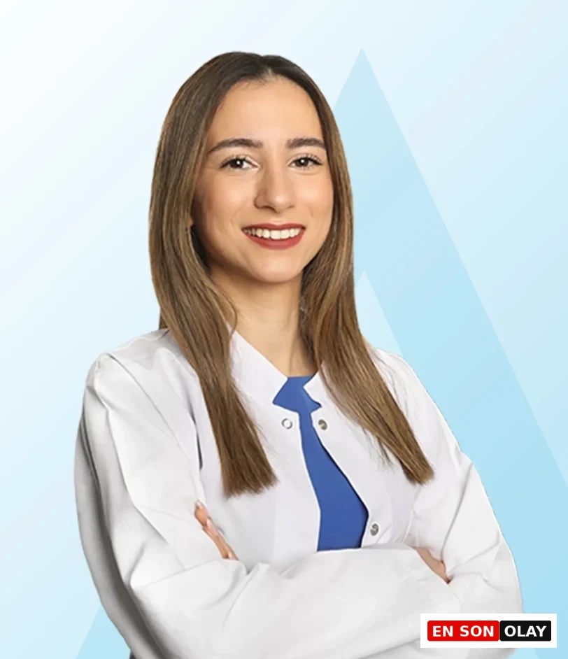Acıbadem Taksim Hastanesi Beslenme ve Diyet Uzmanı Bensu Enyüksek, bağışıklık sistemini güçlendirmenin yolları hakkında bilgi veren makalede, beyaz önlüğü ve mavi bluzuyla kolları bağlı, güler yüzlü bir şekilde kameraya bakıyor.