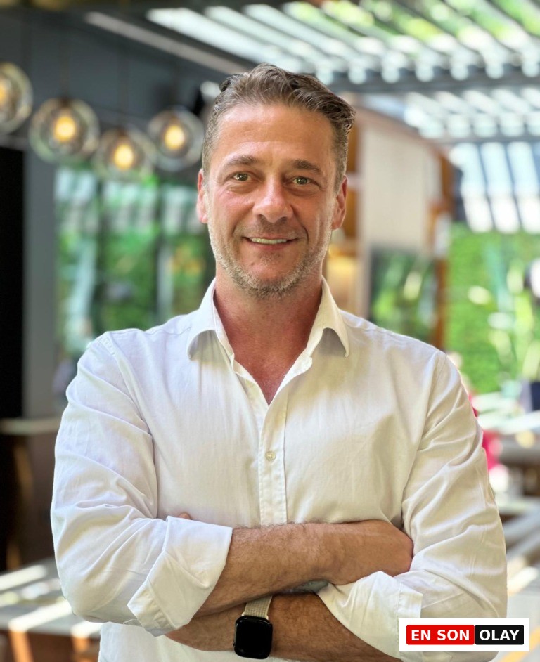 Uzm. Dr. Yıldıray Tanrıver, Infinity Regenerative Clinic Medikal Direktörü olarak, bağışıklık sistemini güçlendirmenin önemli bir yolu olan mikrobiyota dengesi hakkındaki uzman görüşünü paylaşırken, beyaz gömlekli ve kolları kavuşturmuş bir şekilde kameraya gülümsüyor.