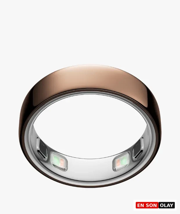 Derin gül rengi parlak metalik Oura Ring, iç yüzeyinde aktif görünen ışık yayan sensörleri ve pürüzsüz dış yüzeyiyle beyaz bir arka plan üzerinde hafif açılı bir şekilde durarak hem zarif tasarımını hem de teknolojik sağlık izleme özelliklerini vurguluyor.