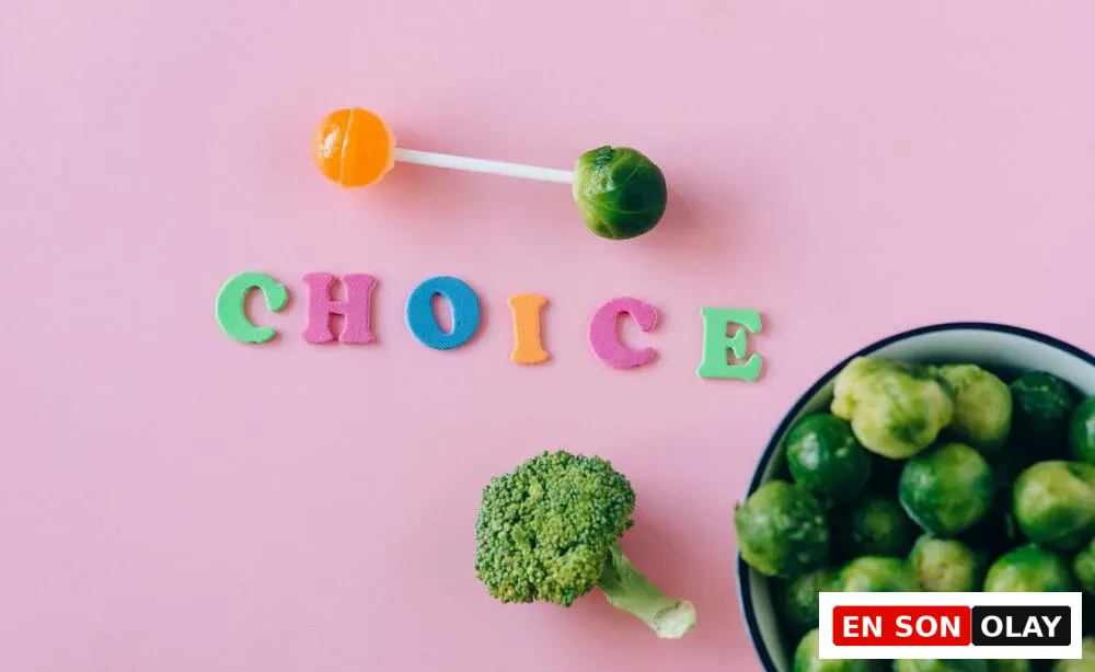 Pembe bir arka planda renkli CHOICE harfleri, bir lolipop ve brüksel lahanasından yapılmış halter figürüyle, yanında duran brokoli ve kase dolusu brüksel lahanaları eşliğinde, kilo verirken kas kaybını önlemek adına sağlıklı beslenme seçimlerinin kritik rolünü vurguluyor.