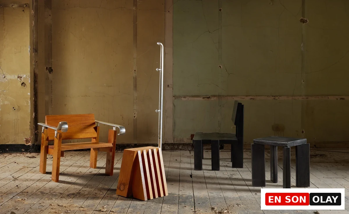 London Design Festival 2026'daki Material Matters sergisinde yer alan, yıpranmış duvarları ve tozlu zemini olan endüstriyel bir ortamda, ahşap ve metalden yapılmış modern tasarımlı bir koltuk, çizgili ahşap bir blok, metal bir askılık, koyu renk ahşap bir sandalye ve küçük bir tabureden oluşan Prima Materia enstalasyonu.