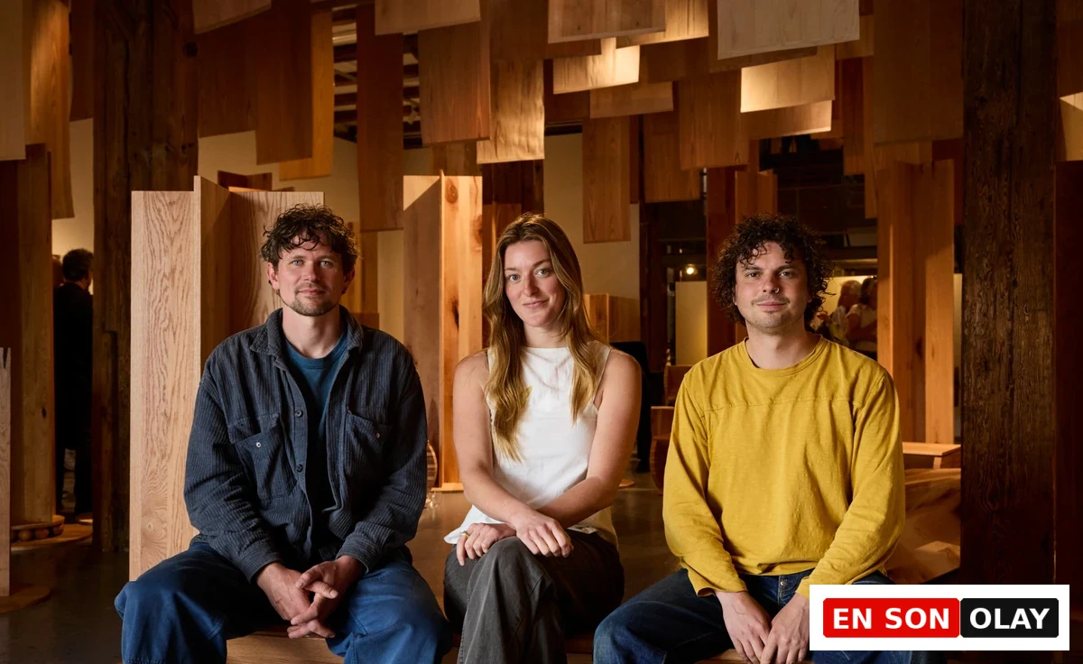 Üç genç tasarımcı, Londra Tasarım Festivali kapsamında Shoreditch Tab Centre'da yer alan Wood for the Trees adlı enstalasyonda, ahşabın ormandan mobilyaya yolculuğunu gözler önüne seren farklı ahşap panellerin ve levhaların oluşturduğu doğal dokulu fonun önünde kameraya bakıyor.