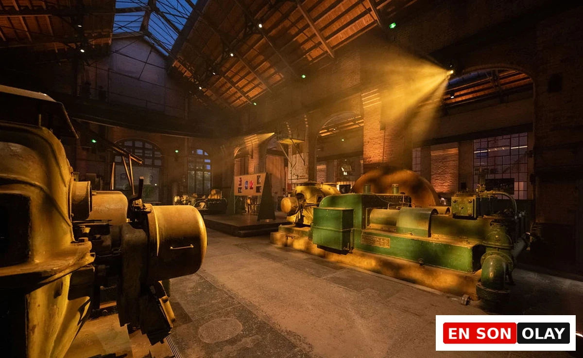 Wapping Hydraulic Power Station’ın yüksek tavanlı tarihi iç mekânında sarı ve yeşil tonlardaki eski hidrolik makineler, tavandan gelen spot ışıkları altında.