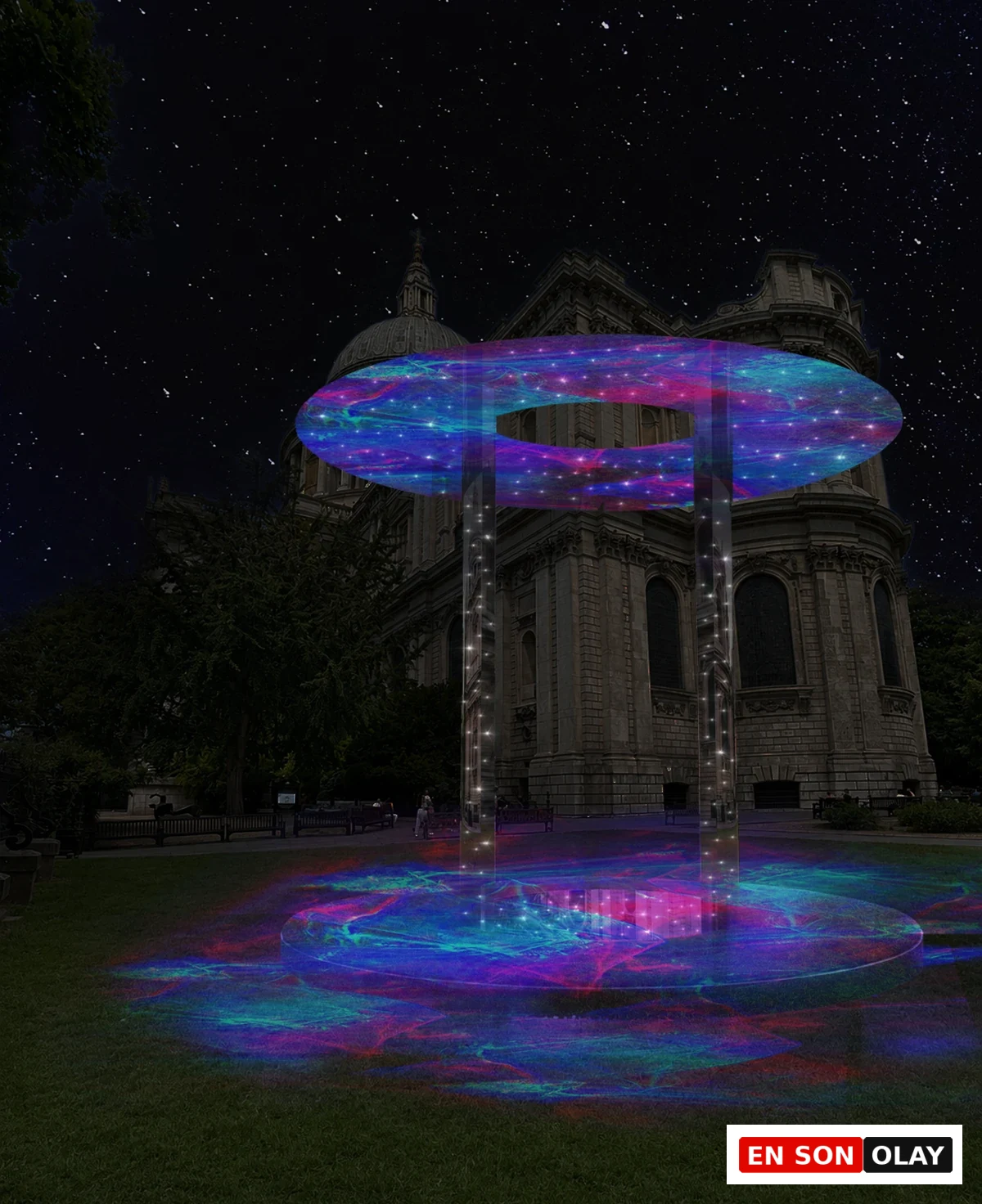 St Paul’s Katedrali’nin tarihi mimarisinin önünde, yıldızlı gece gökyüzünün altında, London Design Festival kapsamında sergilenen, mor, mavi ve pembe renklerde parıldayan ve fiber optik ışıklarla yıldızlı bir halkayı andıran dairesel ışık enstalasyonu, çimenlik alana da yansıyan büyüleyici bir görsel şölen sunuyor.