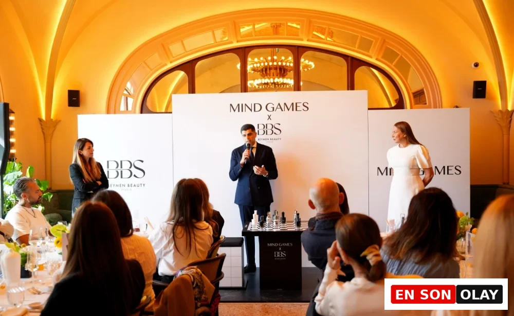 Mind Games Parfüm kurucusu Alex Shalbaf, aydınlık bir iç mekanda, düşünceli ve kendinden emin bir ifadeyle kameraya bakarken, markasının felsefesini yansıtan bu röportaj için sade ve şık bir giyimle poz veriyor.