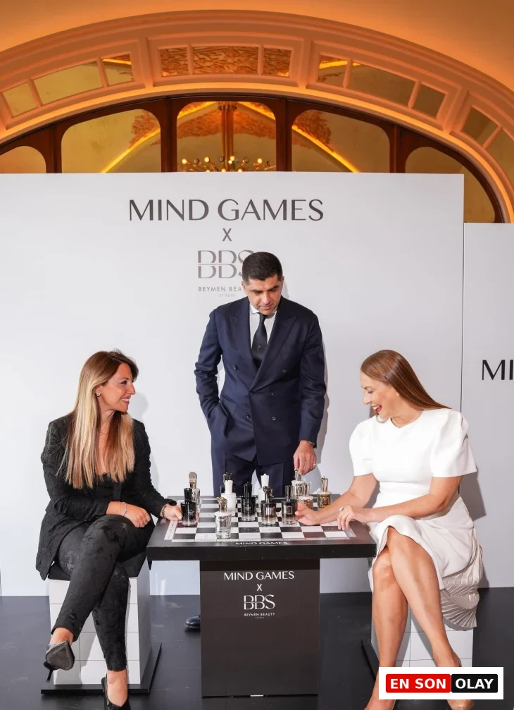 Mind Games Parfüm kurucusu Alex Shalbaf, profesyonel ve özenli bir duruşla, koyu renk takım elbisesi içinde, markasının vizyonunu ve koku dünyasındaki eşsiz yerini anlattığı bu röportajda, kameraya odaklanmış bir şekilde oturuyor.