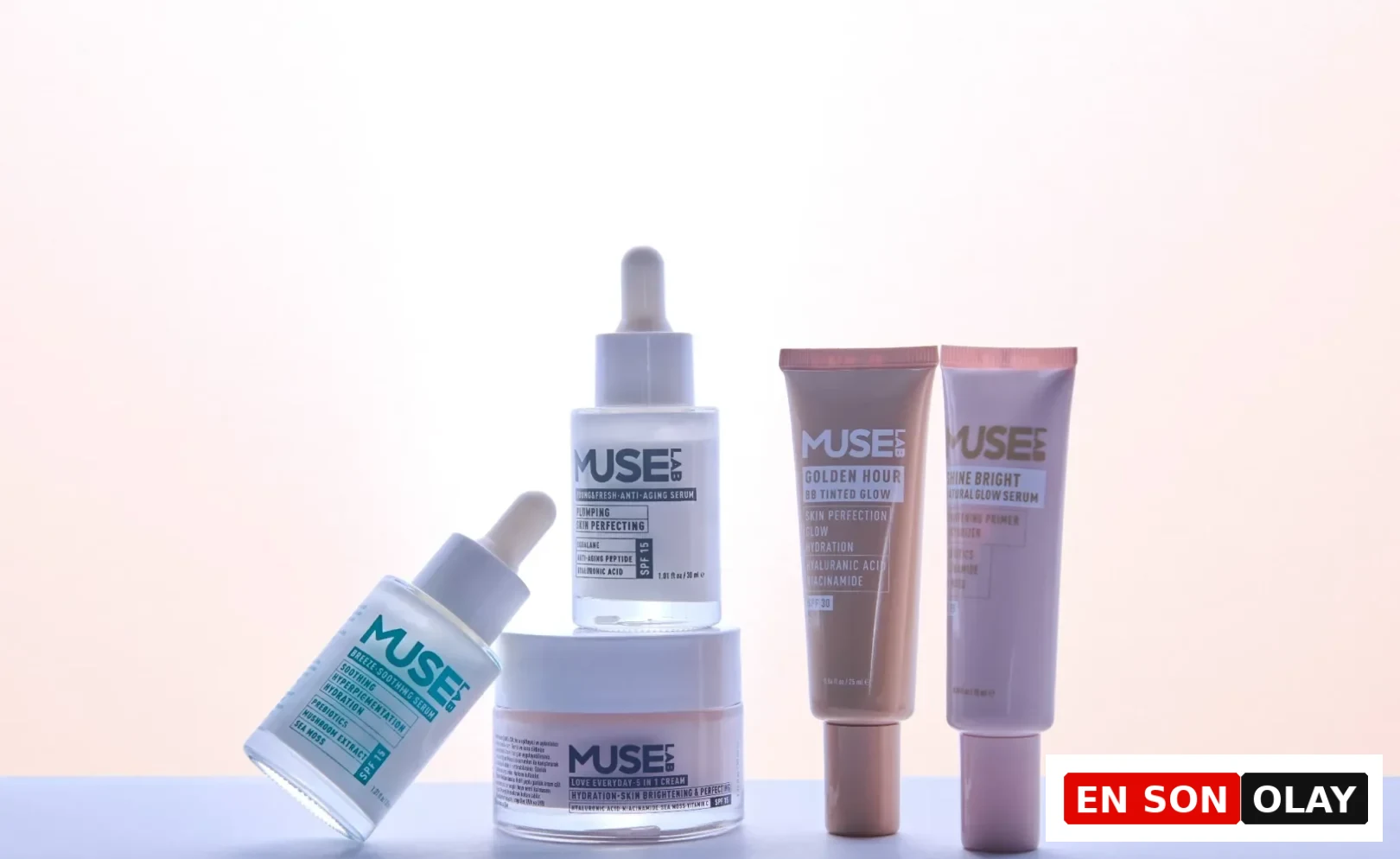 Açık renkli, yumuşak pembe-beyaz bir zeminde, Muse Lab markasına ait, üzerinde SPF korumalı yaşlanma karşıtı serum, nemlendirici krem, leke giderici ve aydınlatıcı serumlar, BB renkli nemlendirici ve makyaj bazı gibi çeşitli cilt bakımı ürünleri estetik bir düzende sergileniyor.