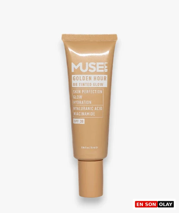 Beyaz bir arka plan üzerinde dikey olarak konumlandırılmış, altın rengi tonlarında, üzerinde MUSE GOLDEN HOUR BB TINTED GLOW yazılı, cilt mükemmelliği, ışıltı ve nemlendirme özelliklerine sahip, SPF 30 korumalı, hyaluronik asit ve niasinamid içeren bir BB kremi tüpü.