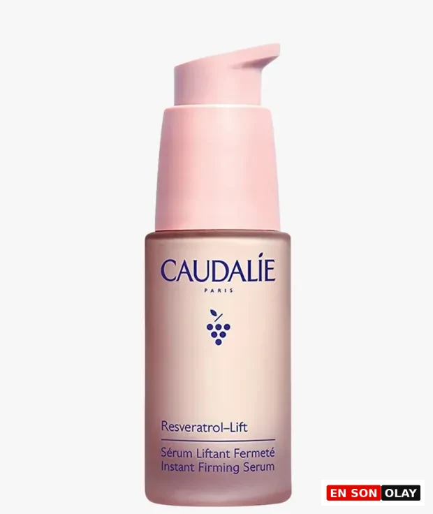 Açık pembe tonlarında, Caudalie markalı, üzerinde üzüm sembolü bulunan zarif şişesindeki Resveratrol-Lift sıkılaştırıcı serum, içeriğindeki Resveratrol ile cilt yaşlanması ve uzun yaşam konularına odaklanan bu rehberdeki cilde faydaları destekliyor.
