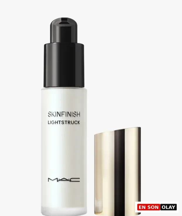 Beyaz, buzlu camdan yapılmış, siyah pompalı aplikatöre sahip, üzerinde belirgin bir şekilde SKINFINISH LIGHTSTRUCK ve MAC logosu bulunan cilt makyajı ürünü, hafif açılı, metalik altın rengi kapağıyla birlikte beyaz bir arka plan üzerinde zarifçe duruyor.
