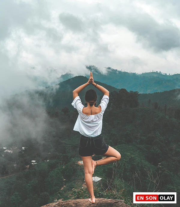 Dağ manzarası önünde yoga yapan kadın, anda kalma ve şükretmenin faydaları teması