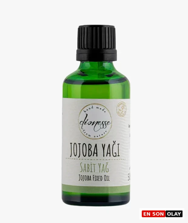 Koyu yeşil cam şişe, siyah vidalı kapağı ve üzerinde büyük harflerle Jojoba Yağı yazan krem renkli etiketiyle öne çıkıyor; bu ürünün özellikle cilt ve saç bakımında kullanılabilen saf soğuk sıkım jojoba yağı olduğunu belirtiyor.