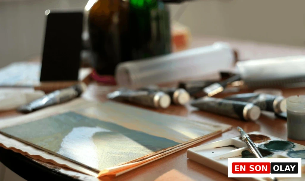 Sanat terapisi için hazırlanmış bir çalışma masası üzerinde akrilik boyalar, fırçalar ve yarım kalmış bir tablo.